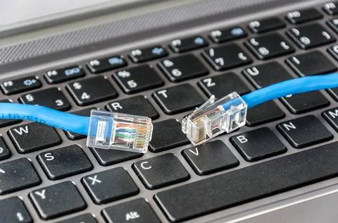 Two internet cables on a computer keyboard symbolizing connectivity issues... Stock Photos