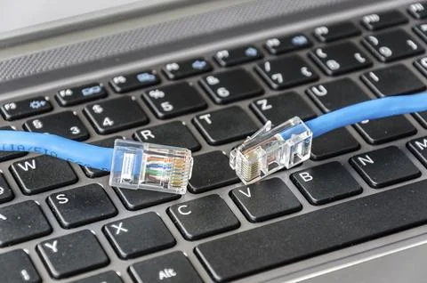 Two internet cables on a computer keyboard symbolizing connectivity issues Stock Photos