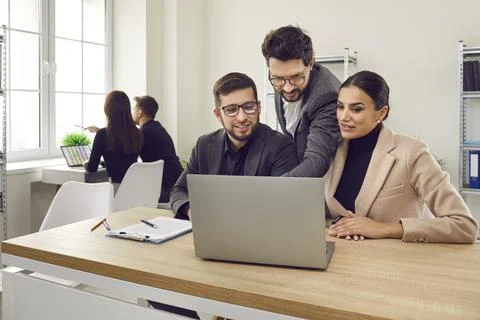 Two interns in office learning new computer software while listening to male Stock Photos