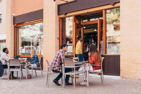 Two interracial couples having a drink at a restaurant terrace Stock Photos