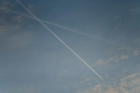 Two intersecting airplane contrails in blue sky Foto stock
