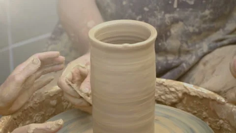 Two intertwined hands form a pot of clay on a potter's wheel.  Stock Footage 87994000