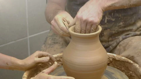Two intertwined hands form a pot of clay on a potter's wheel.  Stock Footage 87994272