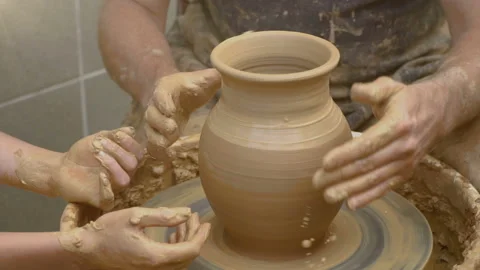 Two intertwined hands form a pot of clay on a potter's wheel.  Stock Footage 87994690