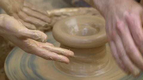 Two intertwined hands form a pot of clay on a potter's wheel.  Stock Footage 106111406