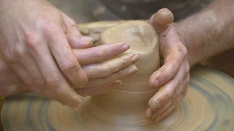 Two intertwined hands form a pot of clay on a potter's wheel.  Stock Footage 106111459
