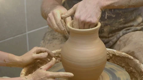 Two intertwined hands form a pot of clay on a potter's wheel. A male hand helps  Stock Footage 106631793