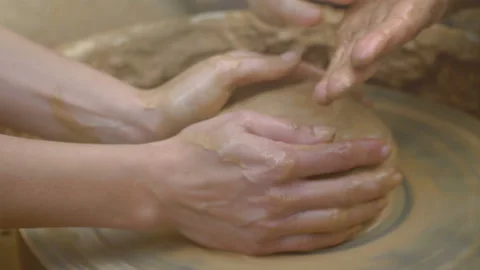 Two intertwined hands form a pot of clay on a potter's wheel.  Stock Footage 136714327