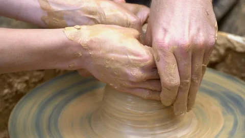 Two intertwined hands form a pot of clay on a potter's wheel.  Stock Footage 136715142