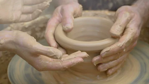Two intertwined hands form a pot of clay on a potter's wheel.  Stock Footage