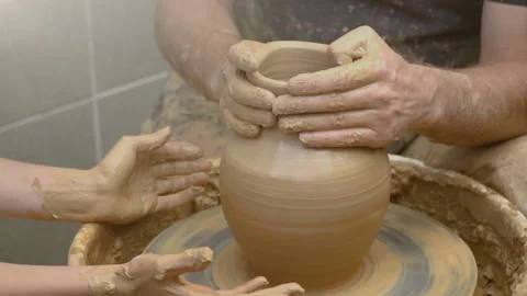 Two intertwined hands form a pot of clay on a potter's wheel.  Stock Footage 136715841