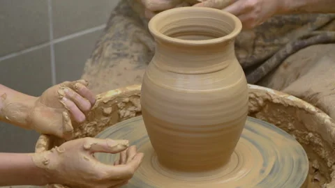 Two intertwined hands form a pot of clay on a potter's wheel.  Stock Footage 136716053
