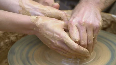 Two intertwined hands form a pot of clay on a potter's wheel.  Stock Footage 136716594