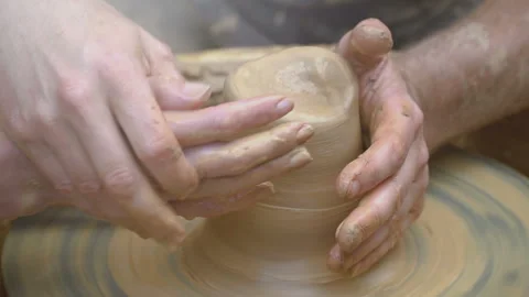 Two intertwined hands form a pot of clay on a potter's wheel.  Stock Footage 136717012