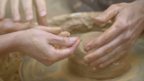 Two intertwined hands form a pot of clay on a potter's wheel.  Stock Footage 136741049