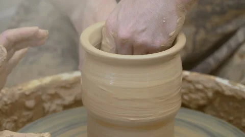 Two intertwined hands form a pot of clay on a potter's wheel.  Video stock 136741843