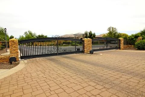 Two Iron Entry And Exit Electric Gates  With Pavers Driveway Stock Photos