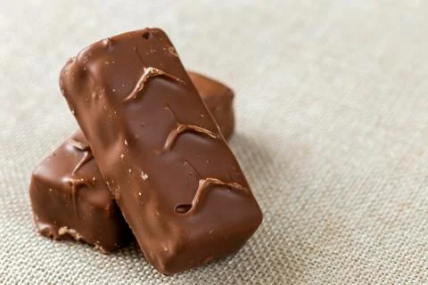 Two isolated isolated dark brown chocolate candy snickers bars on light canva Stock-Fotos