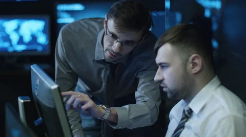 Two IT programmers are working on computers in a dark office room Stock Footage