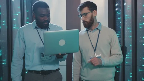 Two IT server engineers using laptop running system diagnostics of rack server Stock Footage 119231992