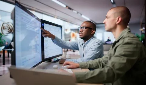 Two IT Service Managers Collaborate At Desk Using Digital Incident System. 스톡 사진