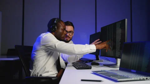 Two IT specialists analyzing data on multiple monitors Stock Footage 305014970