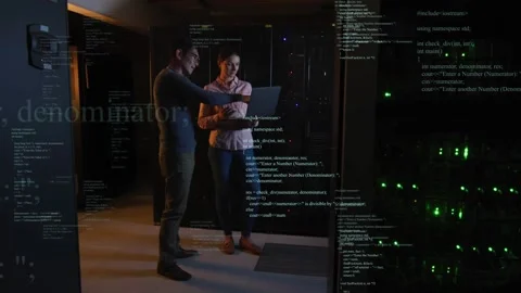 Two IT staff following scrolling code overlay, pointing at laptop and verifying Stock Footage 332544560