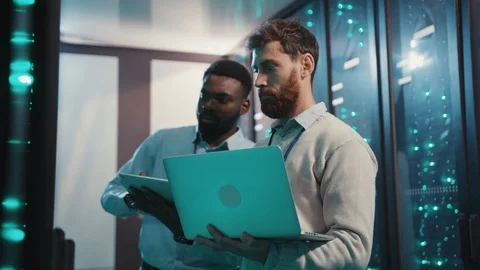 Two IT technicians cooperating collecting network data from rack server cabinets Stock Footage 119232420