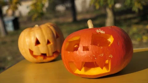 Two jack lanterns stand on the table in the open air. the Halloween pumpkin Video stock 253224322