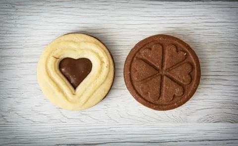 Two jam biscuits in the shape of heart and clover leaf on the wooden backgrou Stock Photos