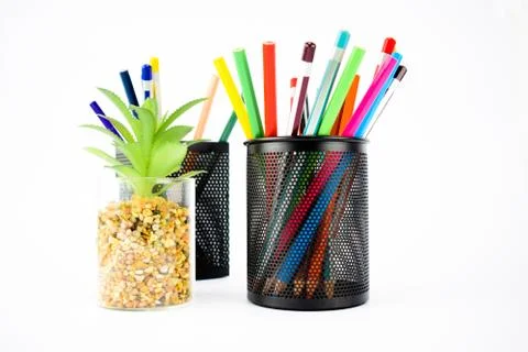 Two jar full of different colored pencil crayons beside a green miniature tre Stock Photos