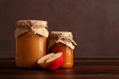 Two jars of apple jam with apple slice on wooden table. Copy space Stock Photos