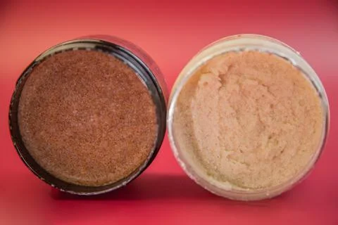 Two jars of body scrub, one brown sugar and one coconut, displayed on a vibrant Stock Photos