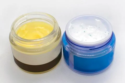 Two jars with different face cream on a white background, dry and oily skin. Stock Photos