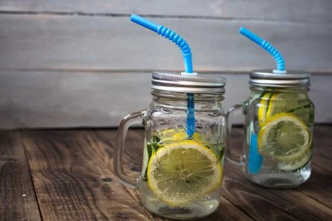 Two jars with a drink with slices of cucumber and lemon Stock Photos