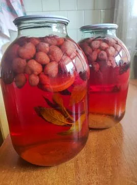 Two jars filled with fruit sitting on top of a wooden table Stock Photos
