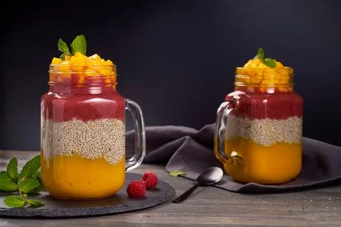 Two jars of layered chia pudding on dark wooden background Stock Photos