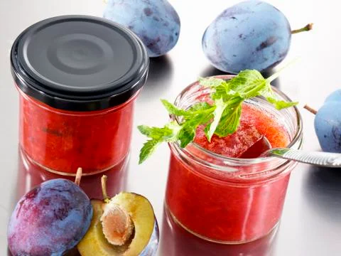 Two jars of plum jam and fresh plums Stock Photos