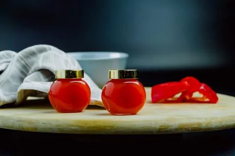Two jars of red pepper jelly on table Stock Photos