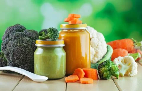 Two jars with vegetable broccoli and carrot puree Stock Photos