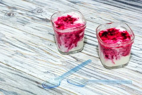 Two jars of yogurt stands on the aged boards Stock Photos