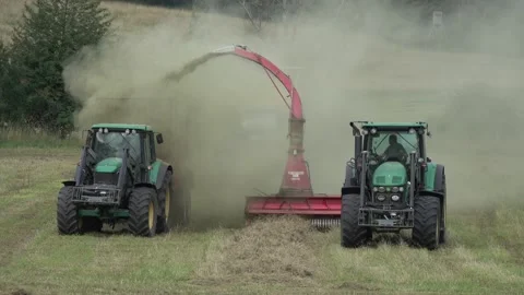 Two John Deere tractors are harvesting dry hay in a meadow and dusting Stock Footage 158500222
