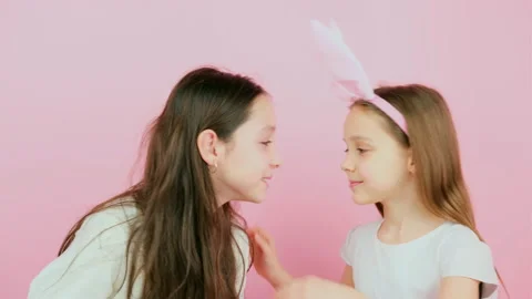 Two joyful sisters, one of them wearing bunny ears on head, touching noses each Stock Footage 171972930