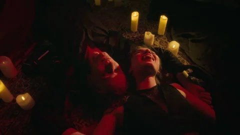 Two Joyfully Smiling Vampires Lying Amidst Circle of Glowing Candles Stock Footage 303983716