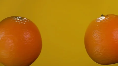 Two juicy oranges are colliding with each other on the yellow background Stock Footage 129117102