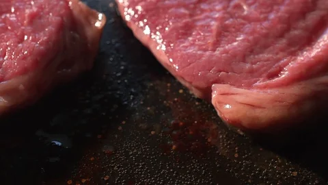 Two juicy steaks sitting on the grill and cooking 스톡 동영상 115779594