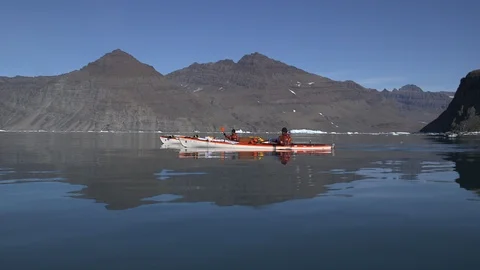 Two kayakers in the Arctic Ocean front of Greenlandic mountains Stock Footage 103505276