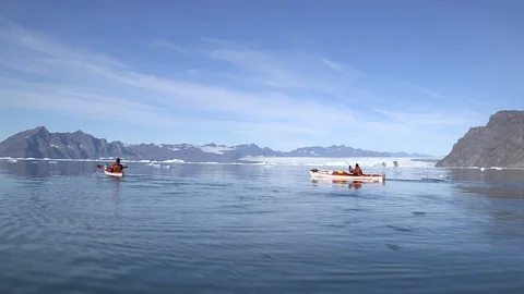 Two kayakers in the middle of the Arctic Ocean front of Greenlandic mountains Stock Footage 103505013