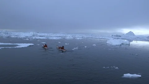 Two kayakers sailing in the middle of the ice floe, Greenland Stock Footage 104184288