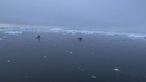 Two kayakers sailing in the middle of the ice floe, Greenland Stock Footage 104184803